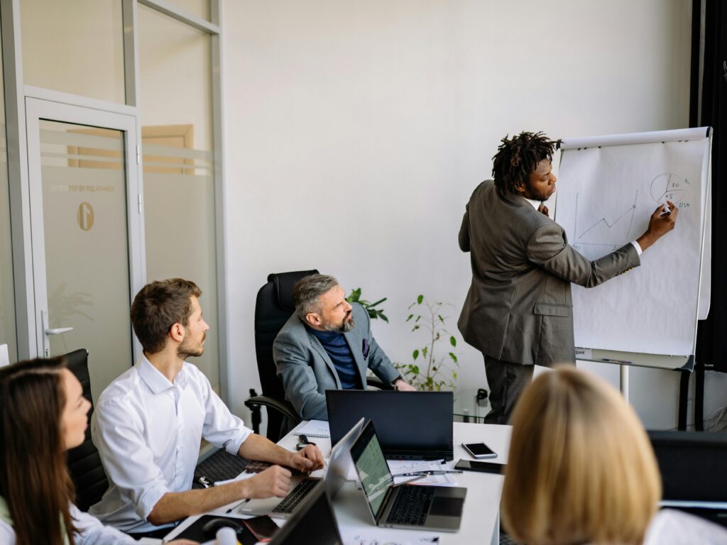 A diverse team in a modern office engaged in a strategic business meeting led by a presenter.